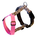 A Y-shape anatomical dog harness featuring a brown and beige cow print pattern with black plastic buckles, a silver metal ring, and a contrasting bright pink adjustable strap.