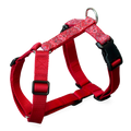 Red dog harness with a red and white paisley pattern on the front straps, black plastic buckles, and a silver metal ring at the top, shown on a white background.