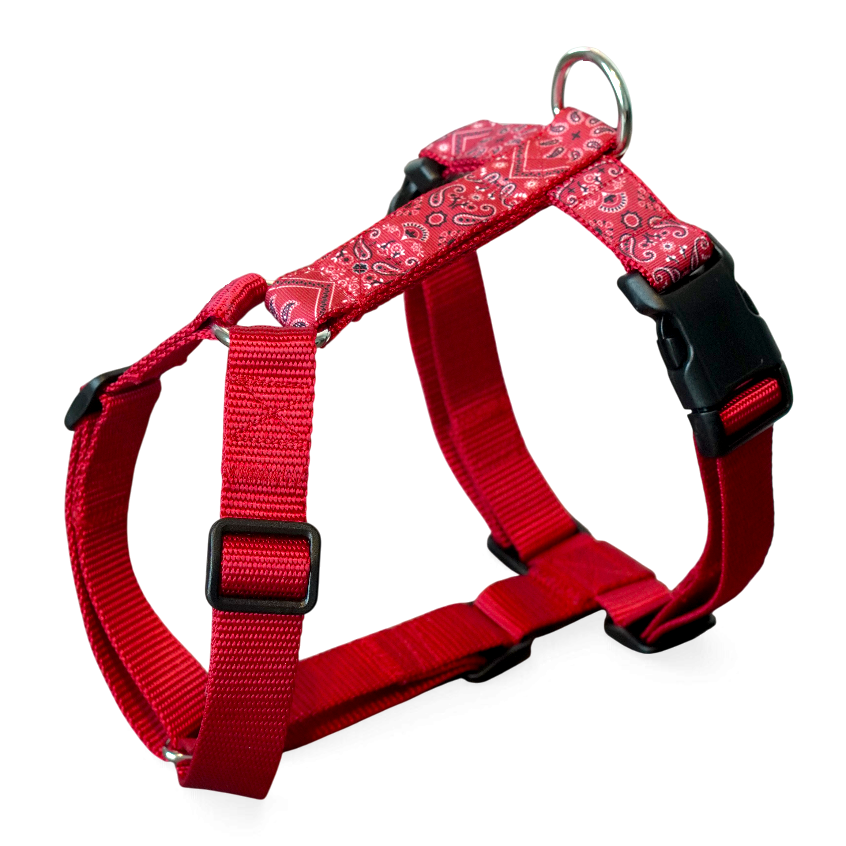 Red dog harness with a red and white paisley pattern on the front straps, black plastic buckles, and a silver metal ring at the top, shown on a white background.